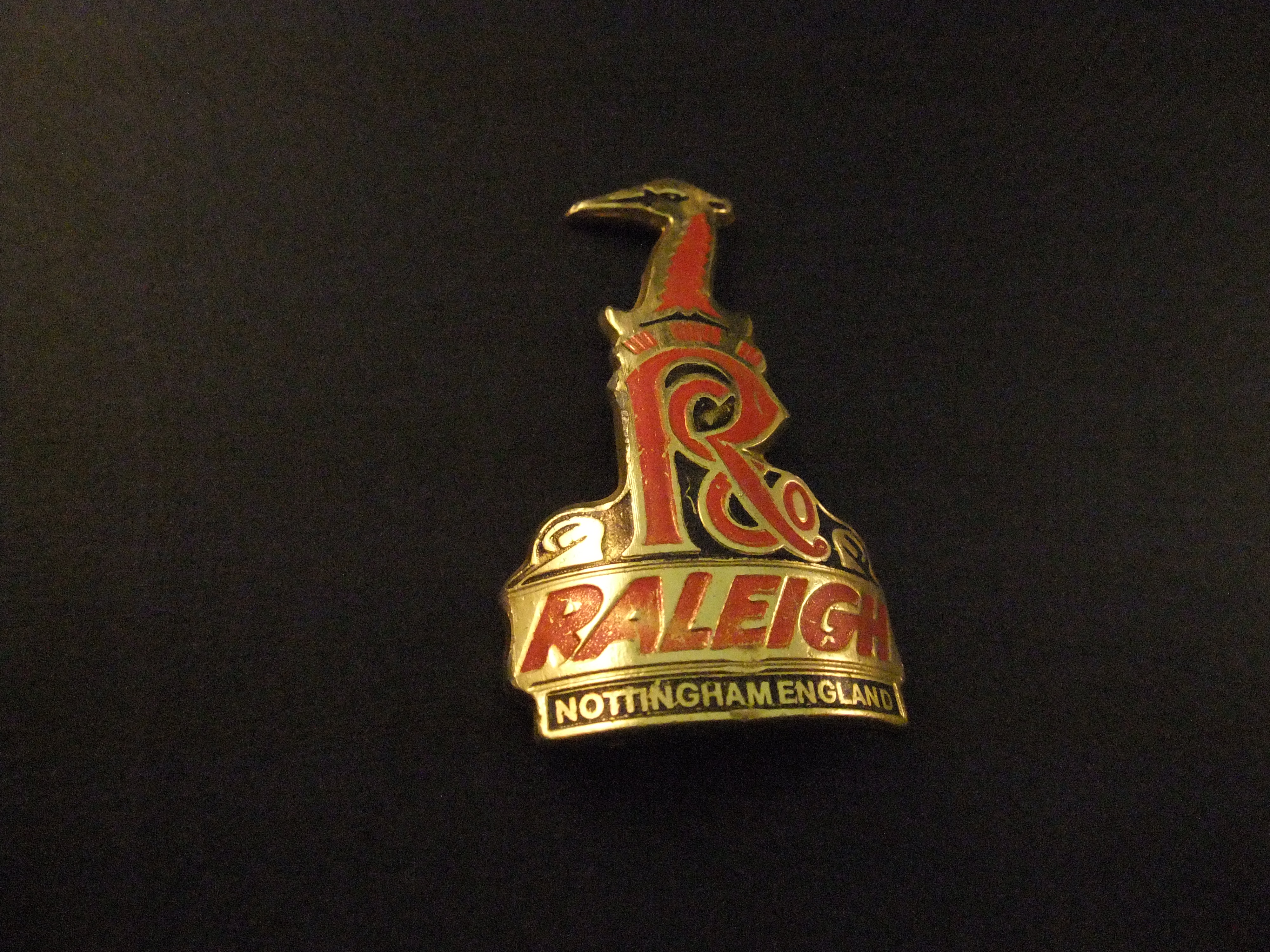 The Raleigh Nottingham England balhoofdplaatje ( goudkleurig-zwarte onderkant)